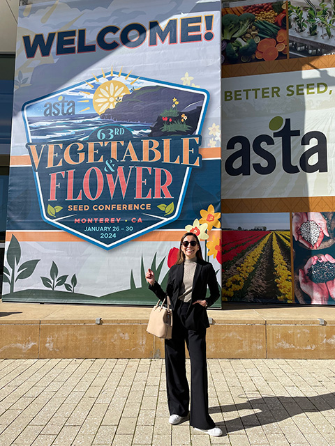 A young woman standing on a sidewalk in front of a large poster.
