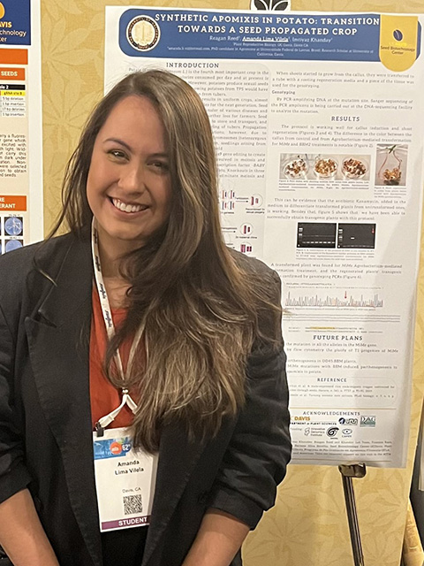 A young woman standing by a research poster and smiling