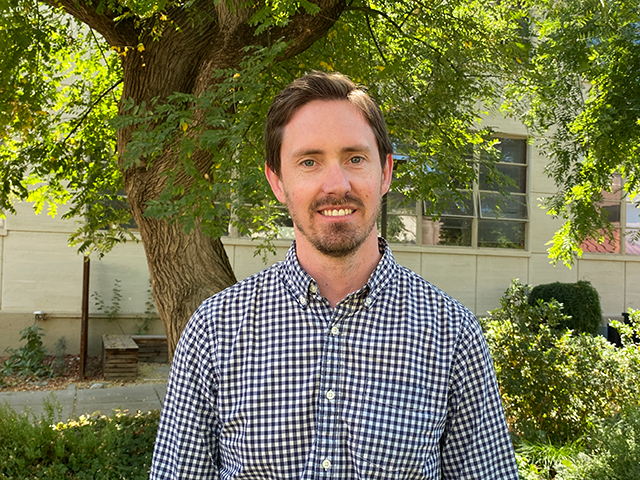 A man standing in a tree-filled courtyard