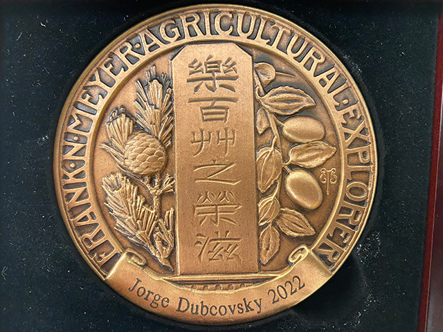 A flat, bronze disk bearing Chinese characters, the name Jorge Dubcovsky and the year 2022.