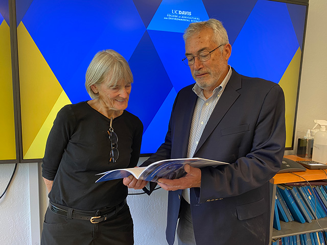 A woman and a man in a room looking at a booklet.