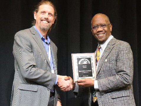 Two men holding a plaque and smiling.