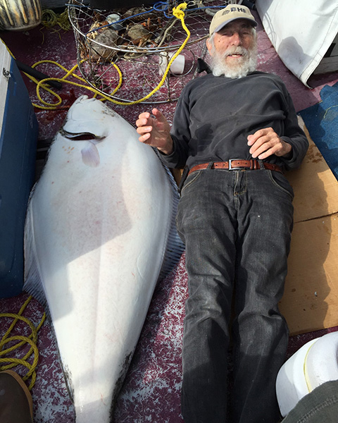 A man laying next to an enormous fish in a boat.