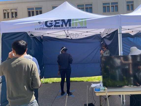 Person under a pop-up tent, wearing a helmet covering their eyes, and standing in an odd pose.