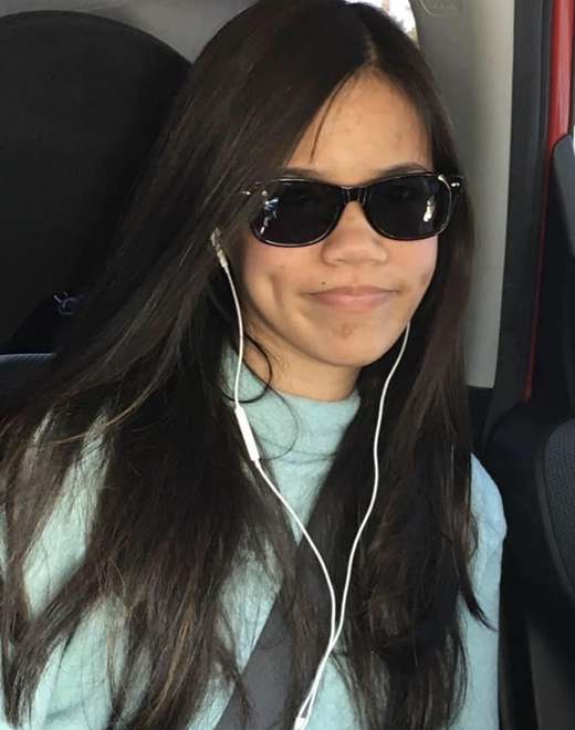 Young woman with long dark hair wearing dark sunglasses
