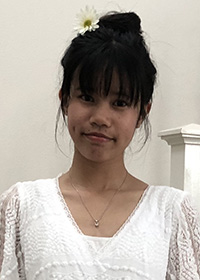 Young woman with black hair up in a bun on top of her head, wearing a white dress