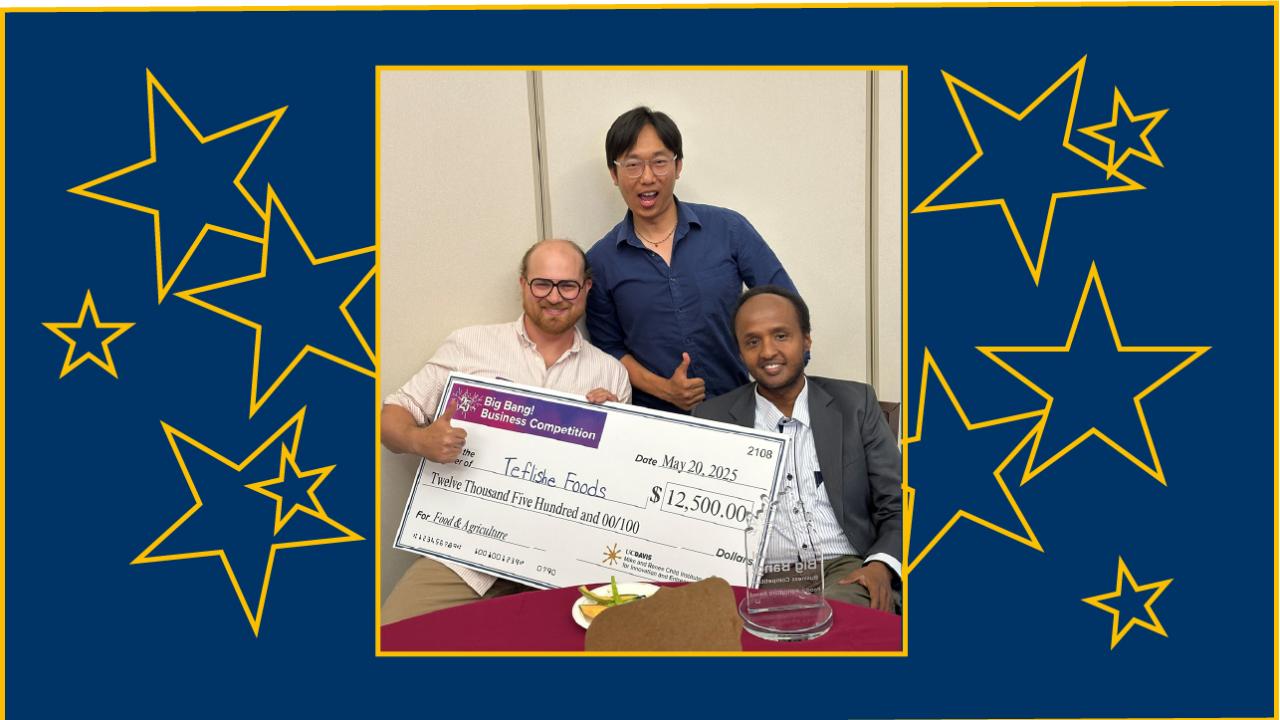 Three young men hold a giant check and are smiling, one gives the thumbs-up