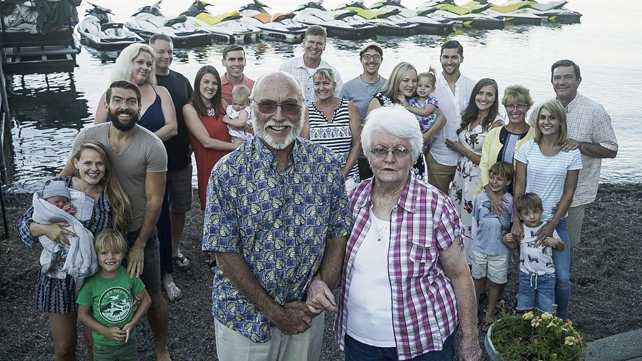 A large family group with children, parents and grandparents, with a lake in the background.