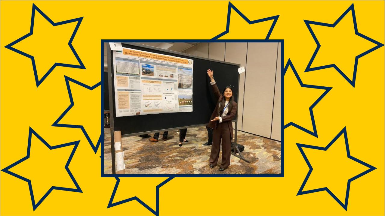 Young woman with arms stretched proudly toward a scientific poster that reads, “Evaluating bacterial diversity and pest control efficacy of steam disinfestation treatments in the Salinas Valley spinach and lettuce fields.”