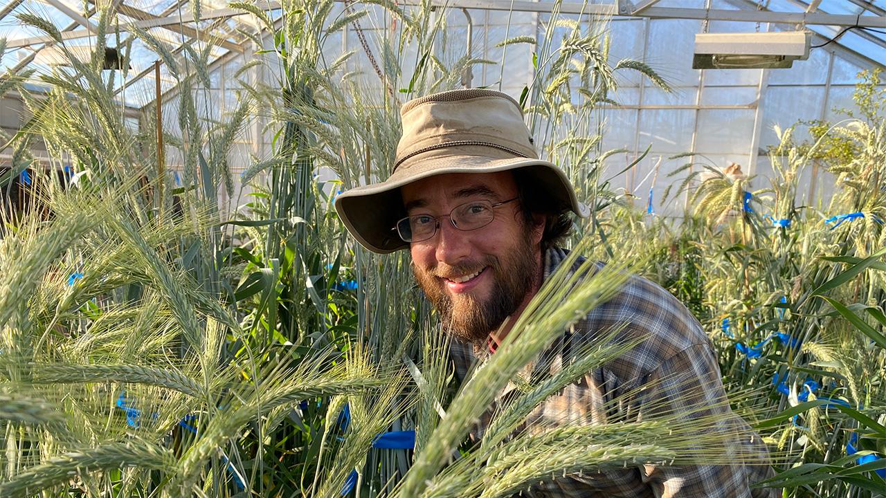 close-up of a man wearing a hat and shown amid spiky green plants