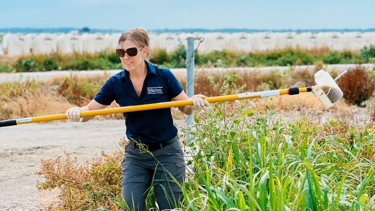 Woman on a farm holding a long pole, some kind of tool.