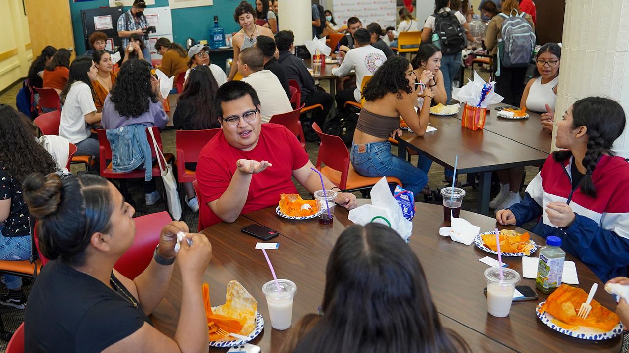 Young people sitting at many tables, laughing and talking.
