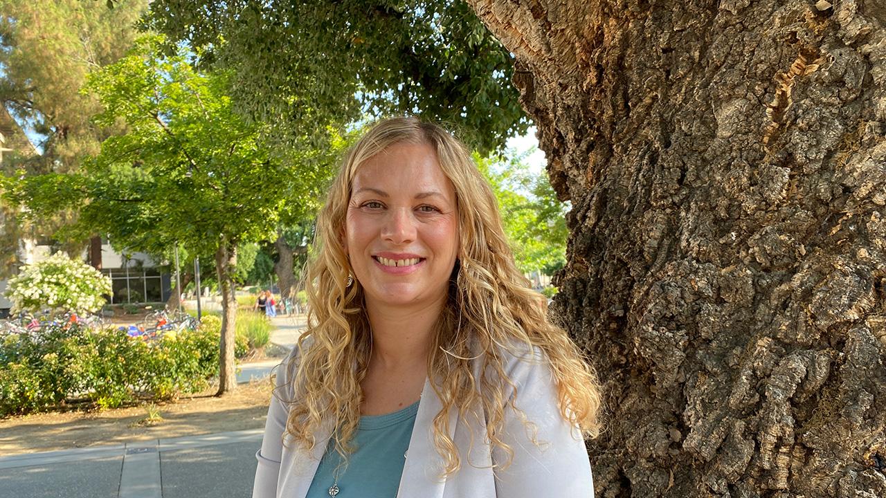 Close-up of a woman standing by a tree.