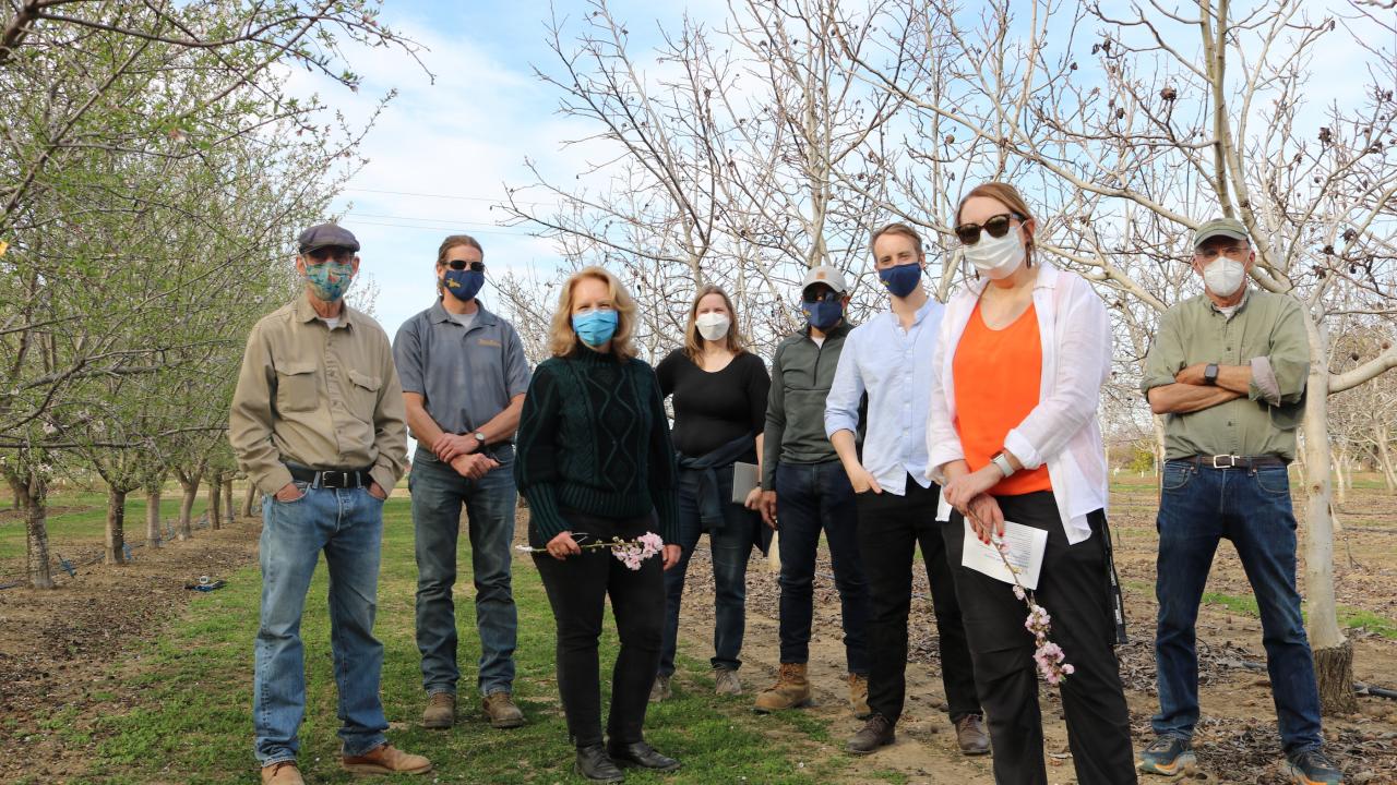 Provost Croughan stands in an orchard row with representatives from the Department of Plant Sciences 