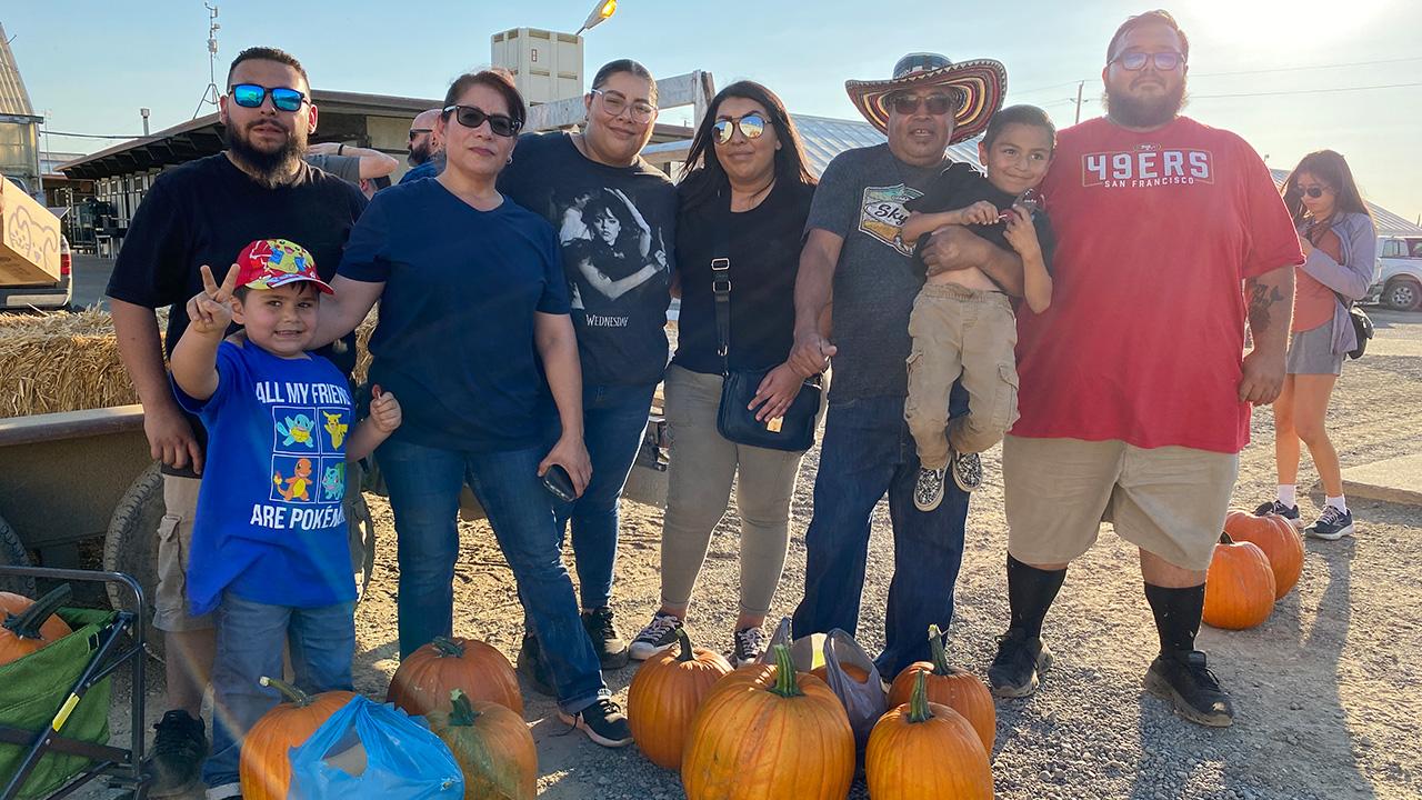 A large family with several large, orange pumpkins.