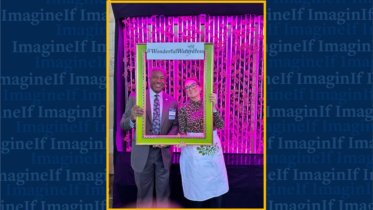 Man and a woman holding a bright green selfie frame that reads, #WonderfulWatercress