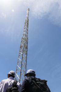 A tower looms overhead, dwarfing those who stand beneath it.