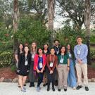 A group of young people standing on a patio with tropical trees in the background.