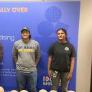 Khushi Chawda stands on the right. She is in front of a banner for her Syngenta Seeds internship. There are three other people in the photo. 