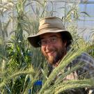 close-up of a man wearing a hat and shown amid spiky green plants