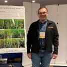 Young man with a scientific poster that reads, “Cattails, Typha L., Control in Delta Rice with Florpyrauxifen"