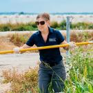 Woman on a farm holding a long pole, some kind of tool.