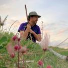 Man sits in peaceful field holding walking stick