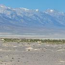 Dry ground, with mountains in the hazy distance. They have a little snow on the peaks.