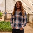 Man in a greenhouse with small, green plants.