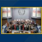 large group of people in a large room with the United Nations symbol above them on the back wall