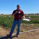 man standing in a field against a blue sky