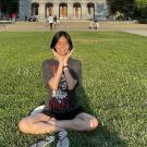 Young woman sitting cross-leged on green grass in front of U.S. Capitol